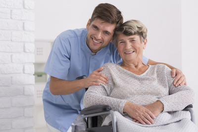 caregiver hugging senior woman sitting in the wheelchair smiling
